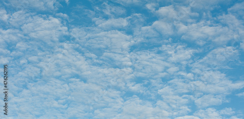 The image with a texture of light, fluffy clouds on the background of a blue sky.