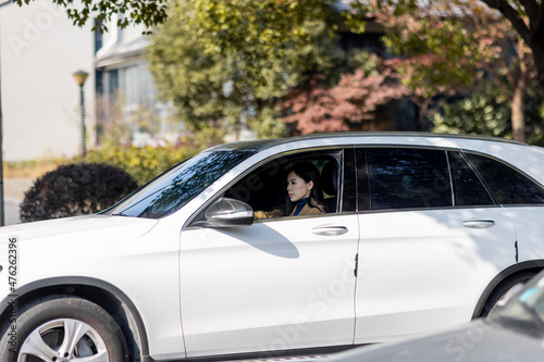 Happy millennial asian woman holding steering wheel when driving car at sunny autumnal day with glad positive emotion  being satisfied with unforgettable journey by car  sitting on seat  enjoying