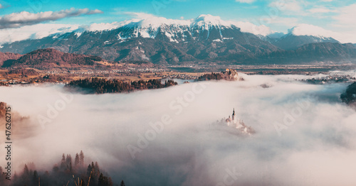 amazing panorama of Lake Bled Blejsko Jezero on a foggy morning with the Pilgrimage Church of the Assumption of Maria on a small island and Bled Castle and Julian Alps in backgroud