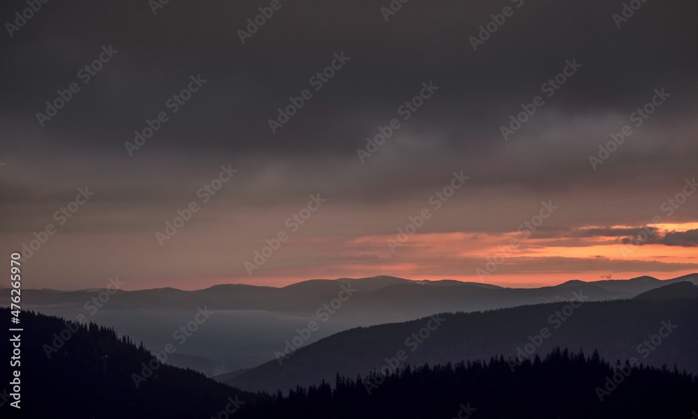 Disturbing sunrise in the mountains. Magnificent view of the clouds illuminated by the rising sun. Disturbing sunrise in the mountains. Magnificent view of the clouds illuminated by the rising sun.