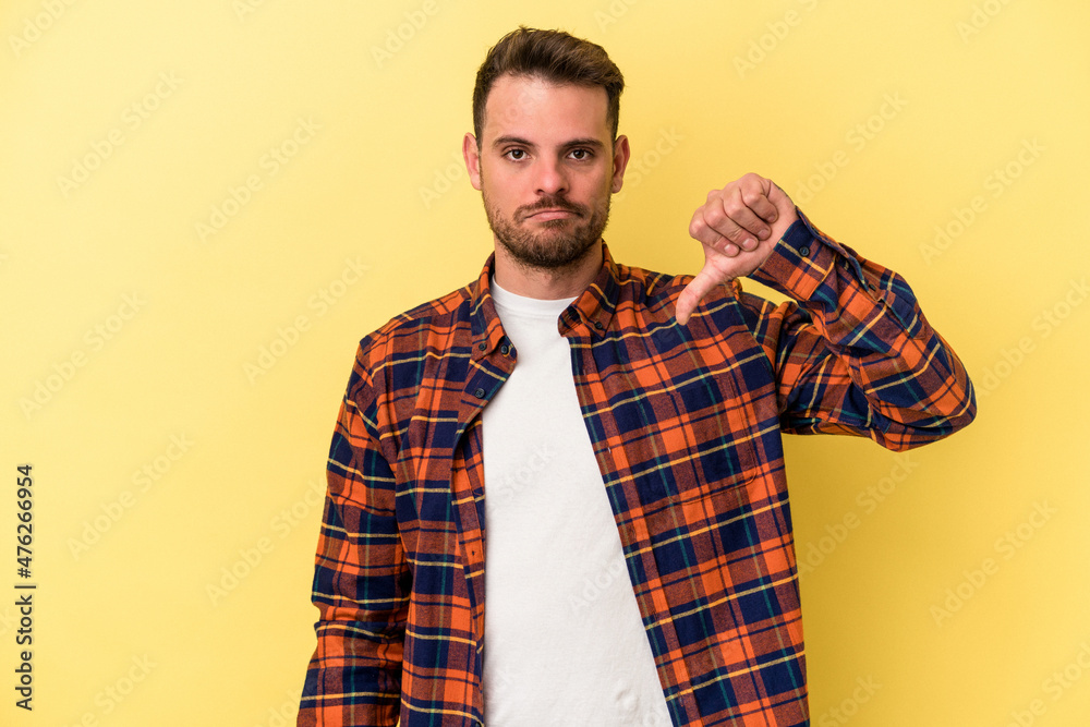 Young caucasian man isolated on yellow background showing a dislike gesture, thumbs down. Disagreement concept. Young caucasian man isolated on yellow background showing a dislike gesture, thumbs down. Disagreement concept.