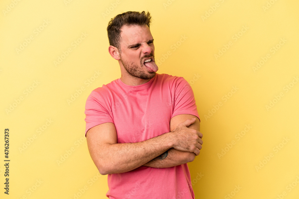 Young caucasian man isolated on yellow background funny and friendly sticking out tongue. Young caucasian man isolated on yellow background funny and friendly sticking out tongue.