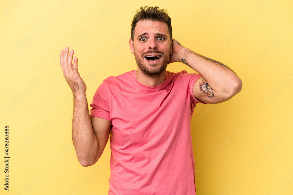 Young caucasian man isolated on yellow background screaming with rage. Young caucasian man isolated on yellow background screaming with rage.