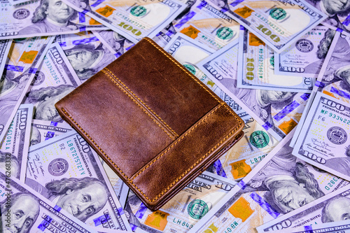 Closed brown leather wallet on the one hundred dollar banknotes