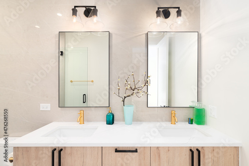 A luxury bathroom with a wooden vanity cabinet  square mirrors  and a white marble countertop.