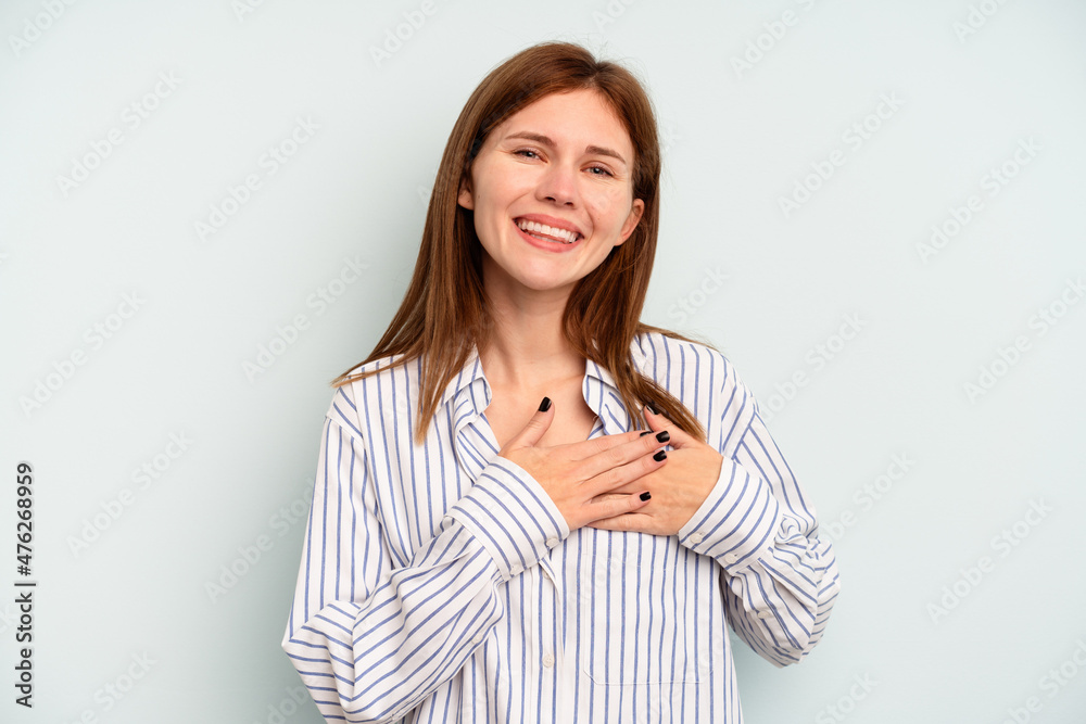Young English woman isolated on blue background has friendly expression, pressing palm to chest. Love concept. Young English woman isolated on blue background has friendly expression, pressing palm to chest. Love concept.