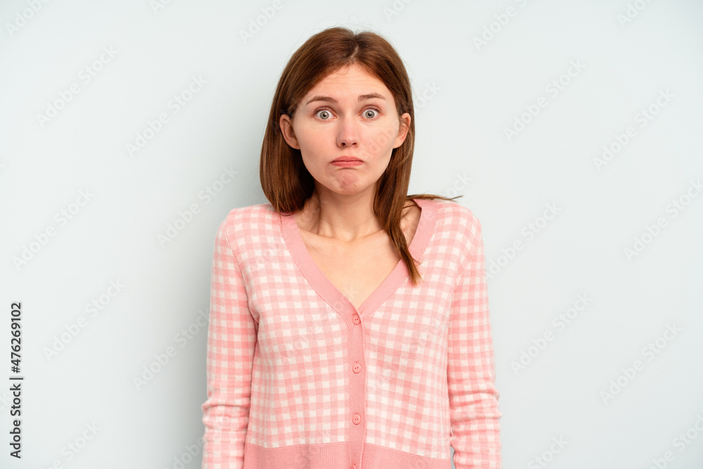 Young English woman isolated on blue background shrugs shoulders and open eyes confused. Young English woman isolated on blue background shrugs shoulders and open eyes confused.