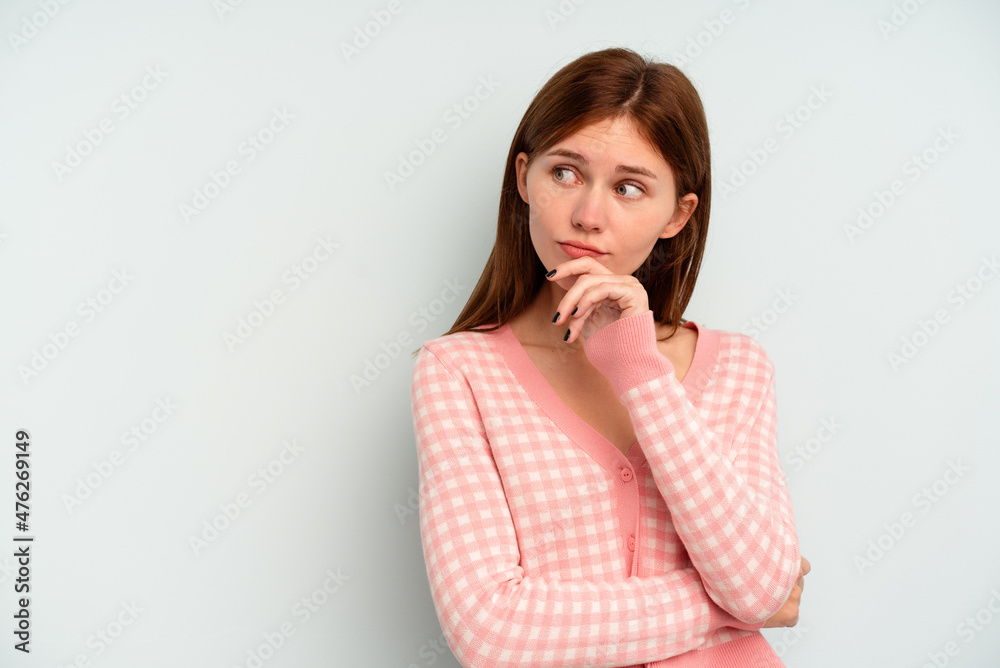 Young English woman isolated on blue background relaxed thinking about something looking at a copy space. Young English woman isolated on blue background relaxed thinking about something looking at a copy space.