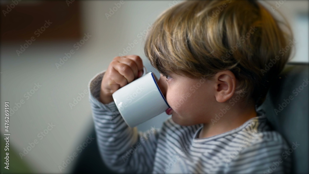 Toddler drinks from mug. Child drinking from cup in morning breakfast. Toddler drinks from mug. Child drinking from cup in morning breakfast.