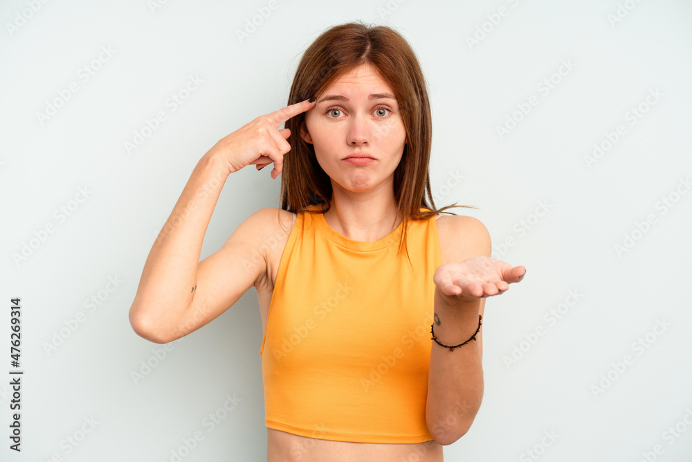 Young English woman isolated on blue background holding and showing a product on hand. Young English woman isolated on blue background holding and showing a product on hand.