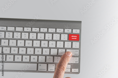 Keyboard with delete covid in red and finger hitting enter photo