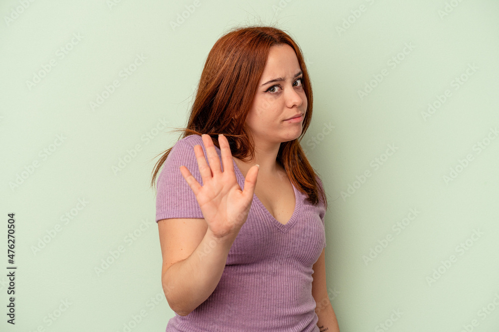 Young caucasian woman isolated on green background rejecting someone showing a gesture of disgust. Young caucasian woman isolated on green background rejecting someone showing a gesture of disgust.