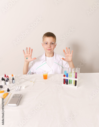 A boy in a white coat. A young chemist. Chemical experience.
