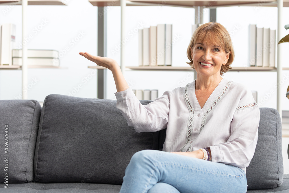 portrait senior woman smiling and raise arm showing pose on sofa