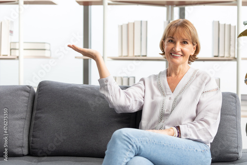 Free Download portrait senior woman smiling and raise arm showing pose on sofa - GFXLoad
