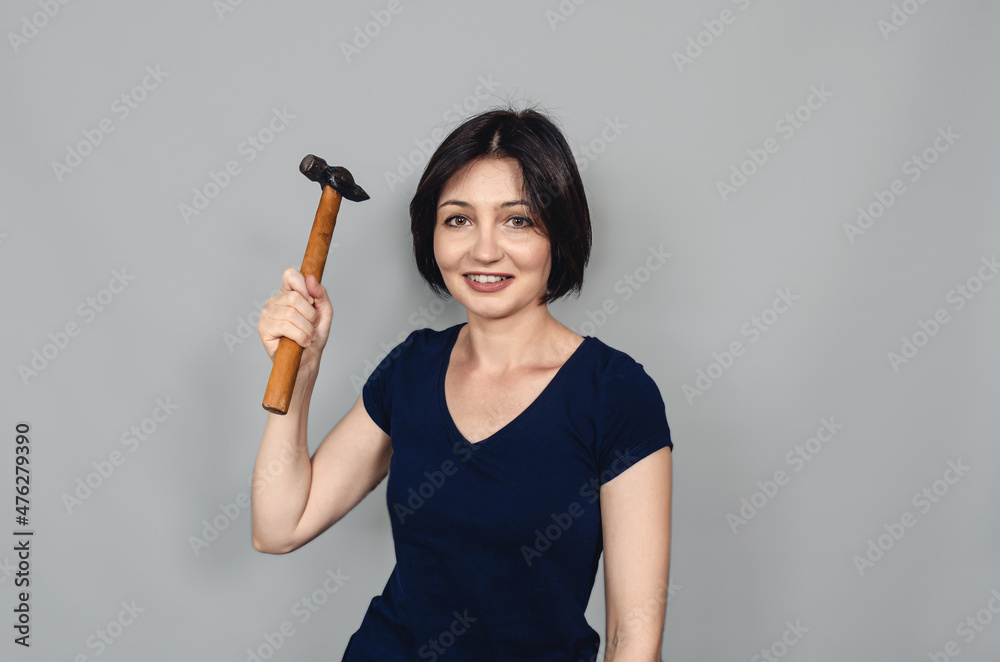 Joyful beautiful dark-haired woman with hammer in her hand. Concept of equality. Joyful beautiful dark-haired woman with hammer in her hand. Concept of equality.