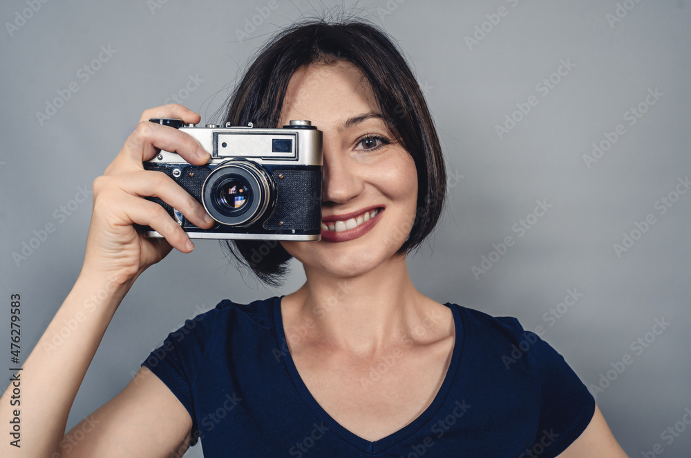 Woman with short black hair holding camera with one hand. Smiling looking at camera. Woman with short black hair holding camera with one hand. Smiling looking at camera.