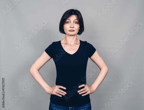 Portrait of beautiful woman with black short hair. Hands on hips. Looking at the camera.