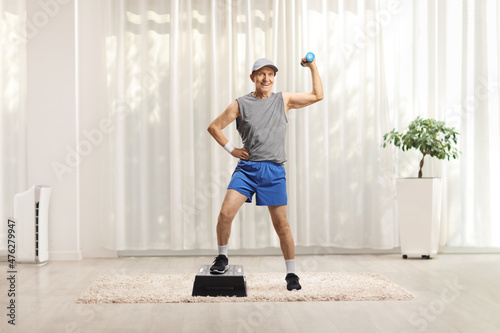 Full length portrait of an elderly man exercising with a step aerobic platform and a small weight