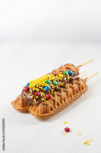 waffles sticks glazed wit chocolate, candies and yellow sprinkles. withe background