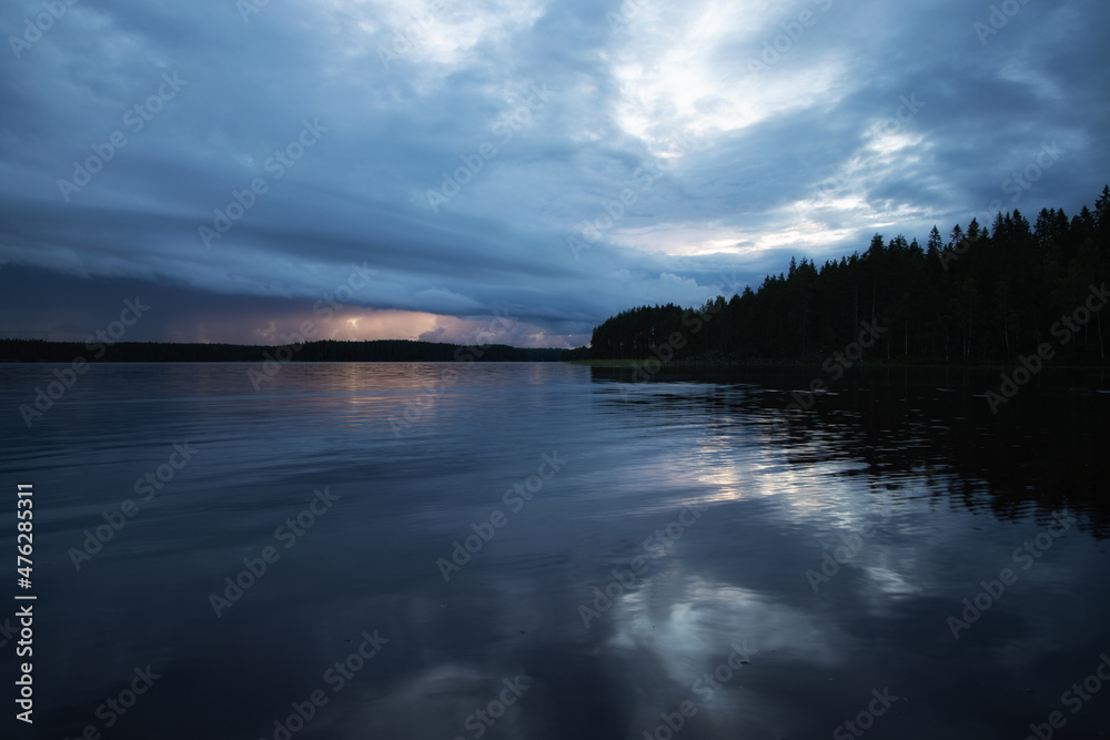 Fototapeta premium Lake under dark storm clouds. Rainy weather landscape.