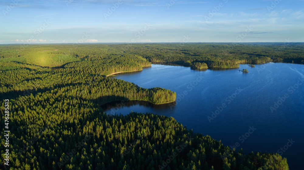 Aerial view of a beautiful sunset over a forest lake reflected in the water, landscape drone shot. Finland.