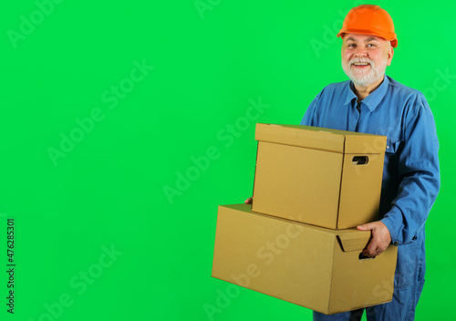 Delivery man in uniform with cardboard boxes. Happy bearded courier with carton box. Copy space.