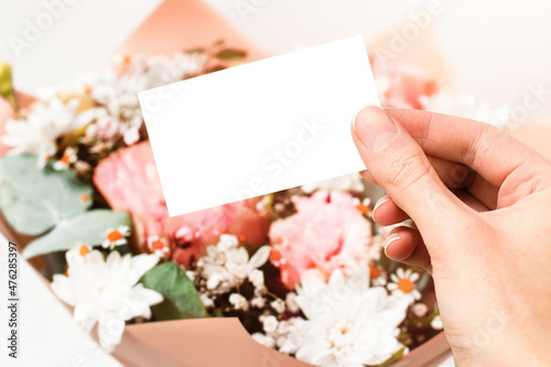 blank note in hand on the background of a bouquet, flower delivery