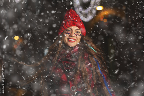 Fototapeta Naklejka Na Ścianę i Meble -  Attractive lady enjoying snowy weather at the holiday fair