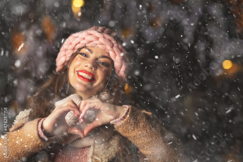 Cheerful lady in gloves enjoying snowfall