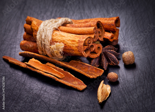 Cinnamon sticks and spieces close up on wooden table. Dark style photo