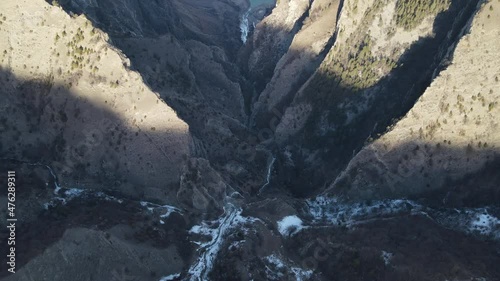 Flying over high cliffs, a waterfall and a beautiful lake high in the mountains. Top view. Aerial video.