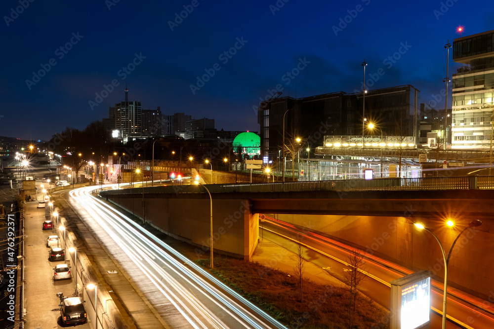 View of the street and modern buildings in the city center. View on the city of Paris at night with cars headlights on a road. Lightpainting scene. View of the street and modern buildings in the city center. View on the city of Paris at night with cars headlights on a road. Lightpainting scene.