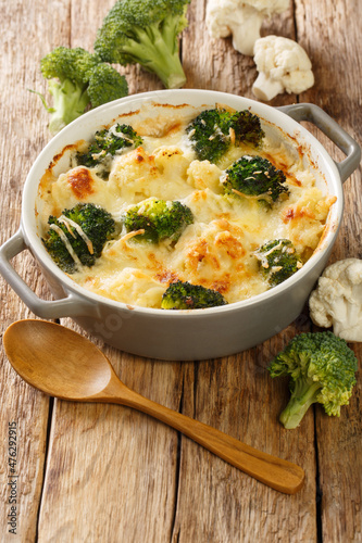 Cauliflower and broccoli baked with cheese sauce in a pot close-up on a table. Vertical