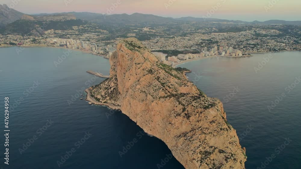 Aerial shot rocky mountain top, drone point of view Penyal d'Ifac Natural Park and Calpe cityscape panorama during dawn. Province of Alicante. Spain. Travel and touristic famous places concept