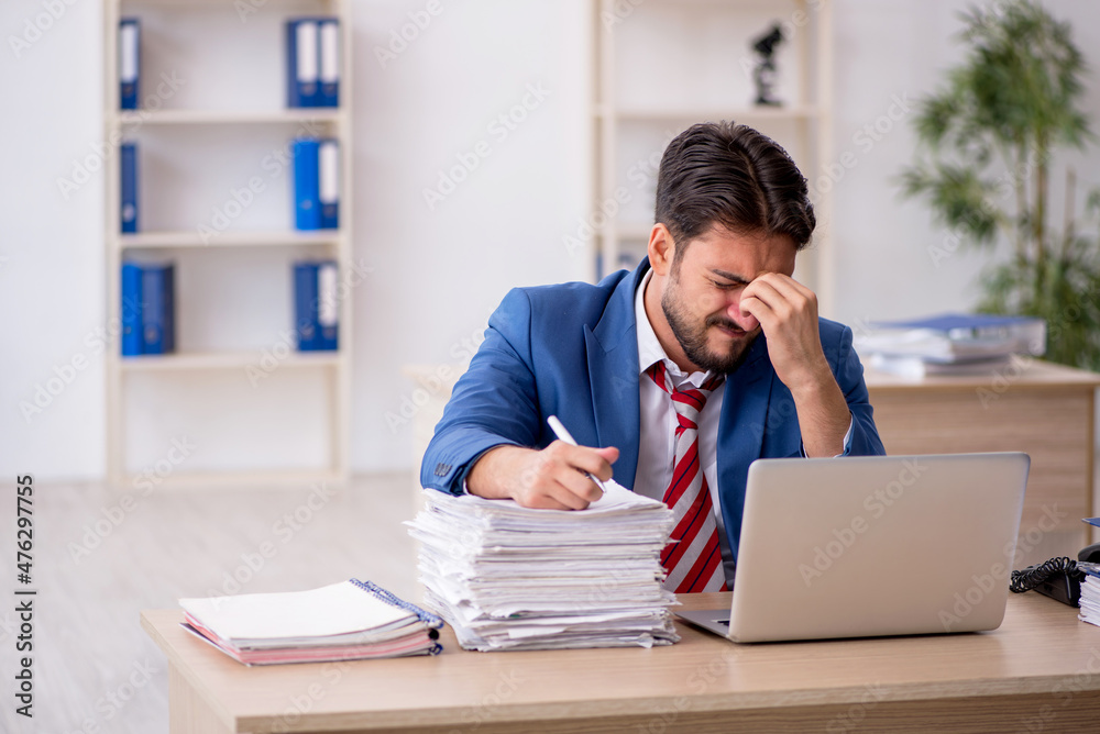 Young male employee and too much work in the office Young male employee and too much work in the office