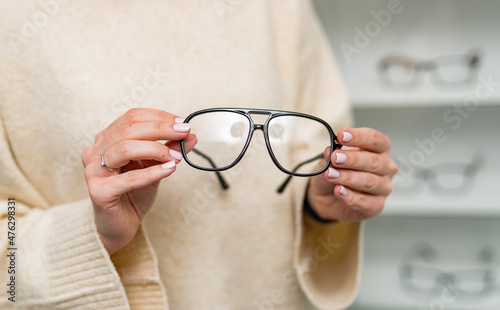 Fototapeta Naklejka Na Ścianę i Meble -  Fashionable eyeglasses lens holding in hands. Eyeglasses in woman hands.