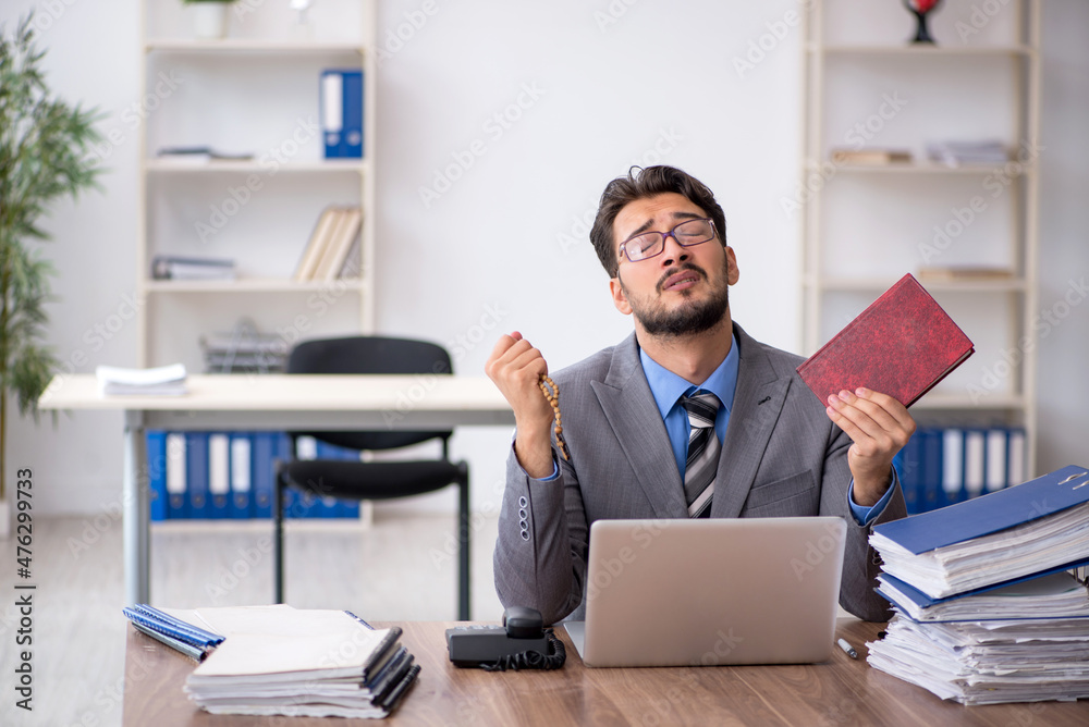 Young male employee unhappy with excessive work in the office Young male employee unhappy with excessive work in the office