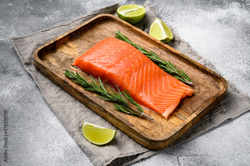 Fresh raw salmon fillet, with herbs, on gray stone table background, with copy space for text
