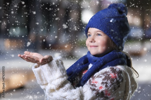 Little cute kid girl having fun on traditional Christmas market during strong snowfall.