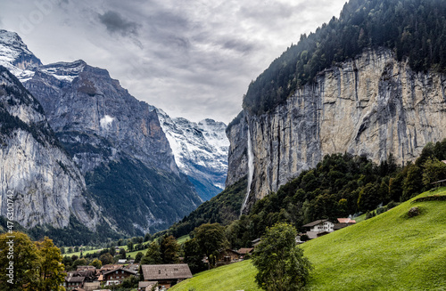 panorama view of cliffs of Swiss alps and the Lauterbrunnen valley with a waterfall cascading over the cliffs and starting close to the town of Murren Switzerland 