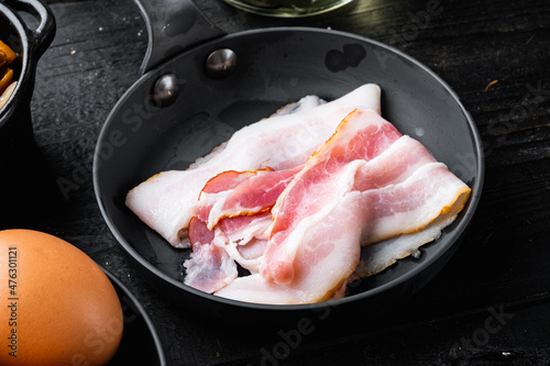 Raw bacon, on black wooden table background