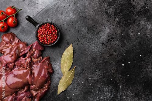 Raw liver chicken offal meat, on black dark stone table background, top view flat lay, with copy space for text photo