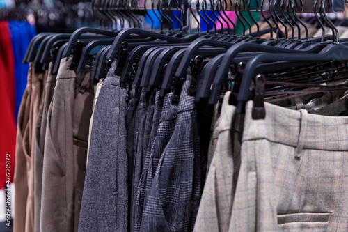 A lot of classic trousers of the autumn-winter collection on hangers in the store. Close-up. Selective focus.