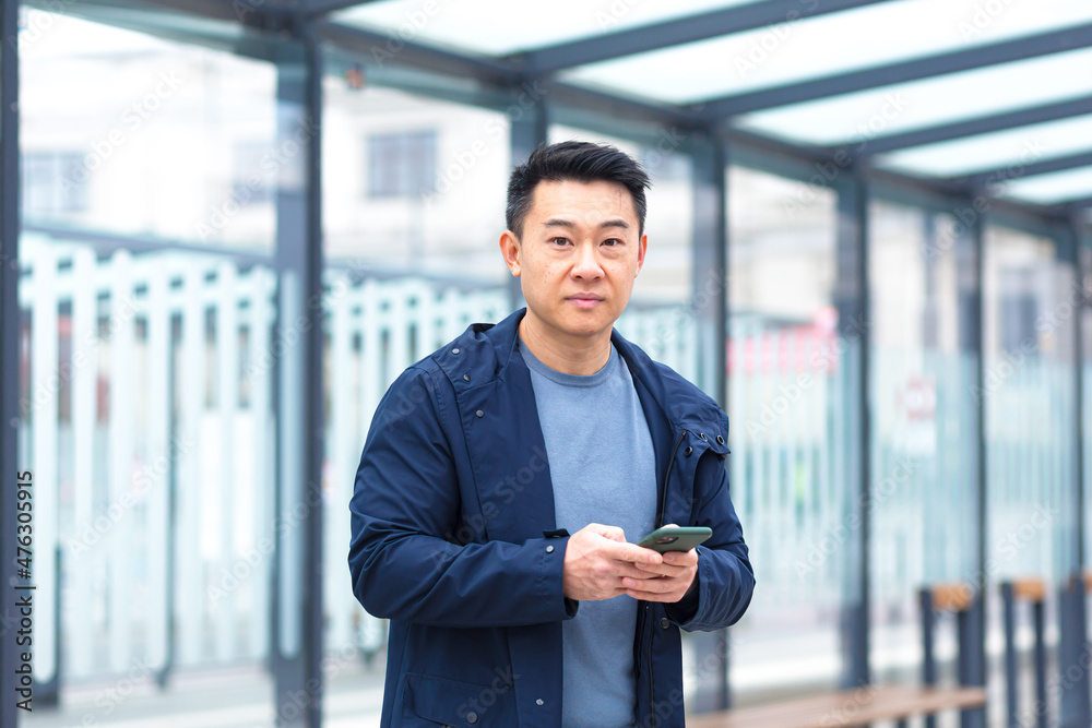 Thinking Asian, business man uses phone, near modern office, and airport Thinking Asian, business man uses phone, near modern office, and airport