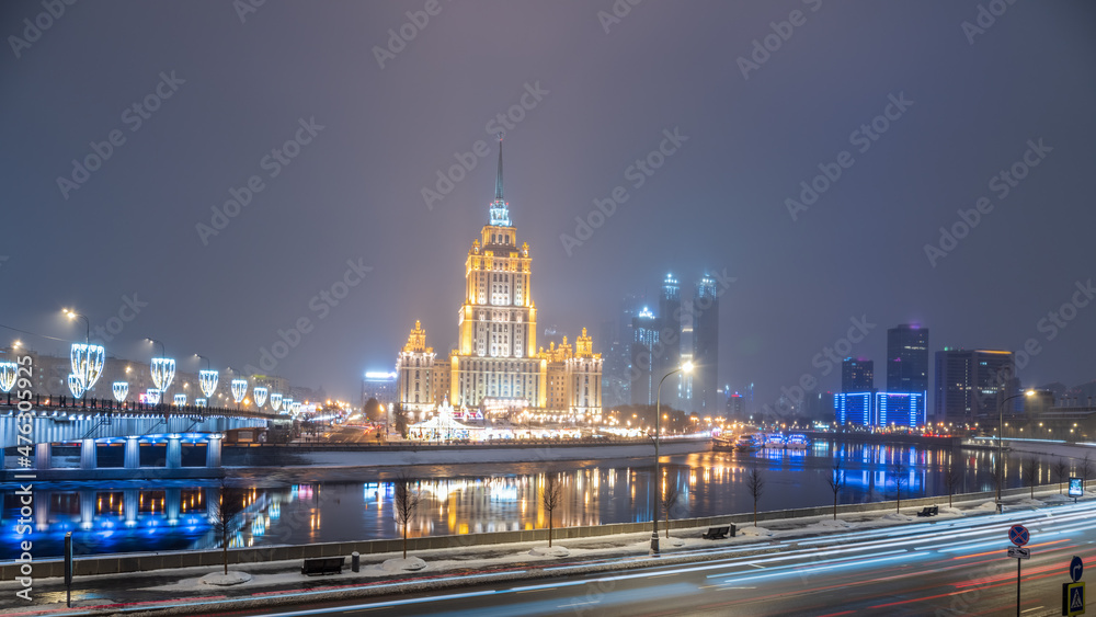 Illuminated high-rise stalinist building near river at winter night in Moscow, Russia. Historic name is Hotel Ukraine.