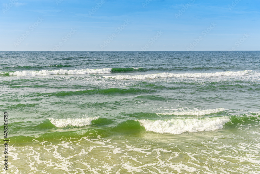 Seascape with incoming waves on the sandy shore.