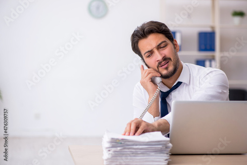 Young male employee unhappy with excessive work in the office