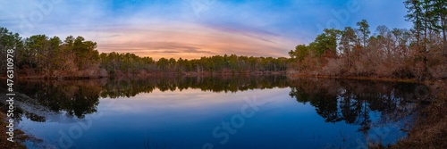 Fototapeta Naklejka Na Ścianę i Meble -  Tranquil panoramic lake and forest landscape at sunset on Cape Cod. Winter blue colors on the sky and water reflections.