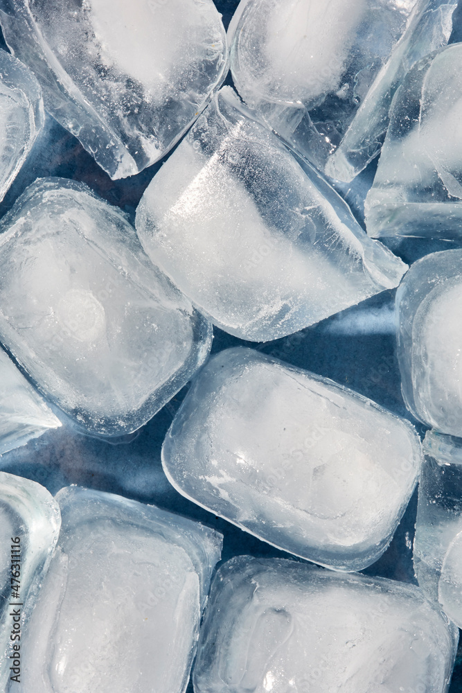 Fototapeta premium Top view of ice cubes in a glass bowl on a blue background